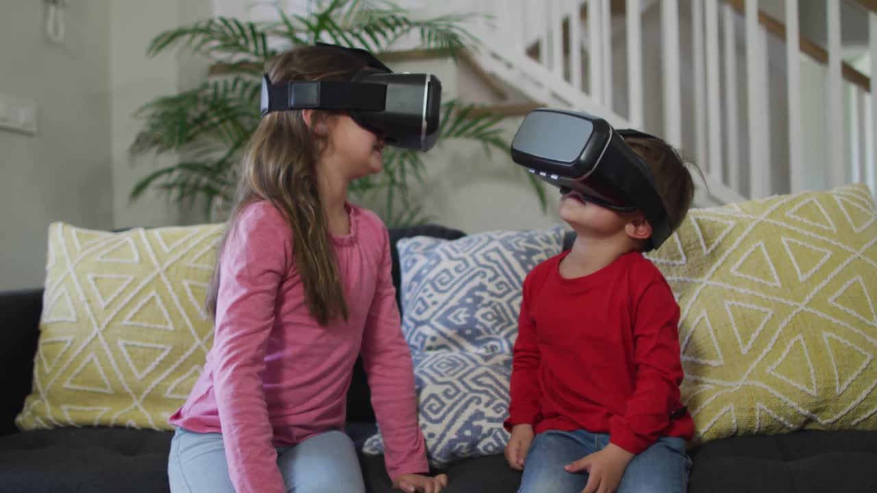 hermanos caucásicos usando auriculares vr, sentados en el sofá y divirtiéndose