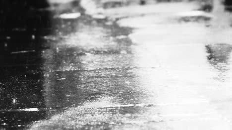 Gotas-De-Agua-De-Lluvia-Ligera-Que-Caen-Sobre-La-Carretera-De-Asfalto-Que-Refleja-La-Luz-Brillante-En-Un-Día-Oscuro-Y-Sombrío