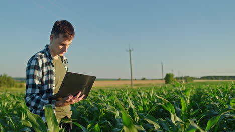 agricultor usando una computadora portátil en un campo de maíz