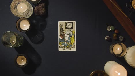 überkopfschuss einer person, die tarotkarten liest, die den tod, die gerechtigkeit und die hierophant-karten auf dem tisch darstellt