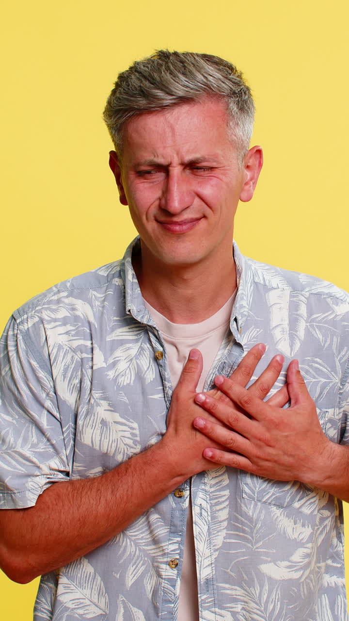 Adult man clutching chest and bending forward in pain suffering from sudden heartache health issue