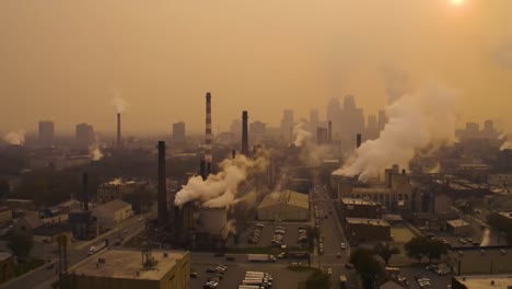 aerial view of urban industrial landscape shrouded in haze with emissions from factories against the backdrop of a smoky sunset