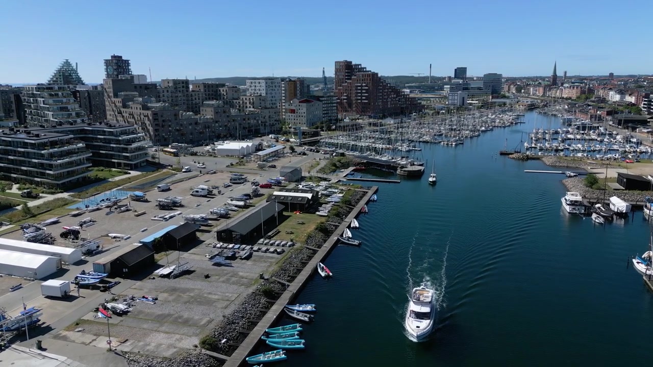 Marina e canale portuale fiancheggiati da barche ed edifici moderni nella zona portuale di Aarhus, regione emergente e vivace, Danimarca, panoramica aerea introduttiva
