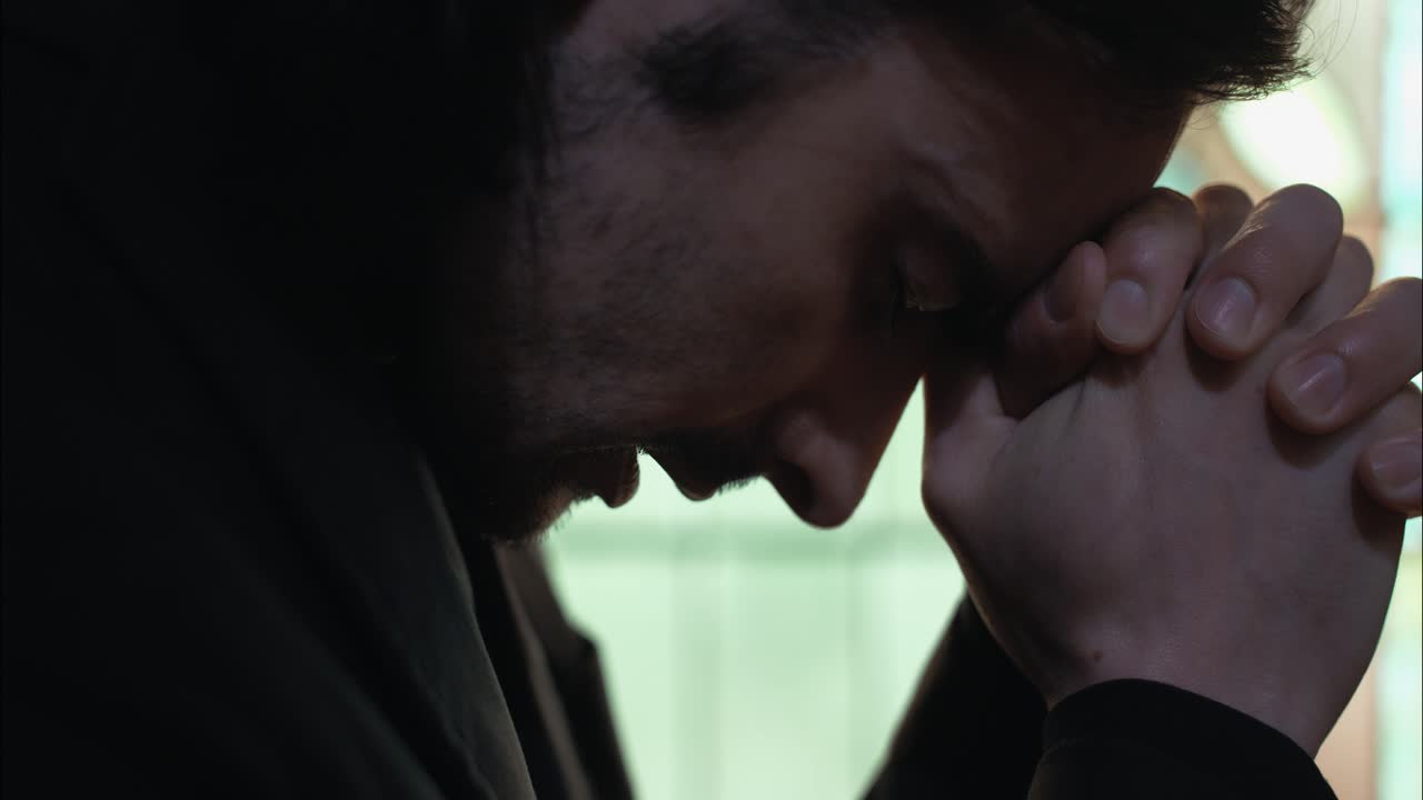 오래된 교회 건물에서 유리창 앞에 무을 고 기도하고 배하는 젊은 남자