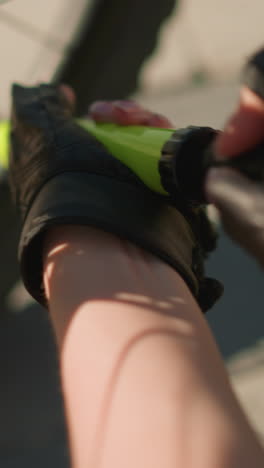 primer plano de una mano con guantes bombeando firmemente aire en el neumático de la bicicleta utilizando una boquilla verde bajo la luz del sol brillante, enfoque detallado en las manos y la bomba, con un suave borrón de fondo