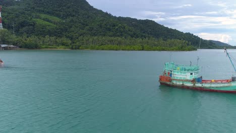 Drone-shot-of-a-wooden-fishing-boat-towing-a-sinking-boat-behind