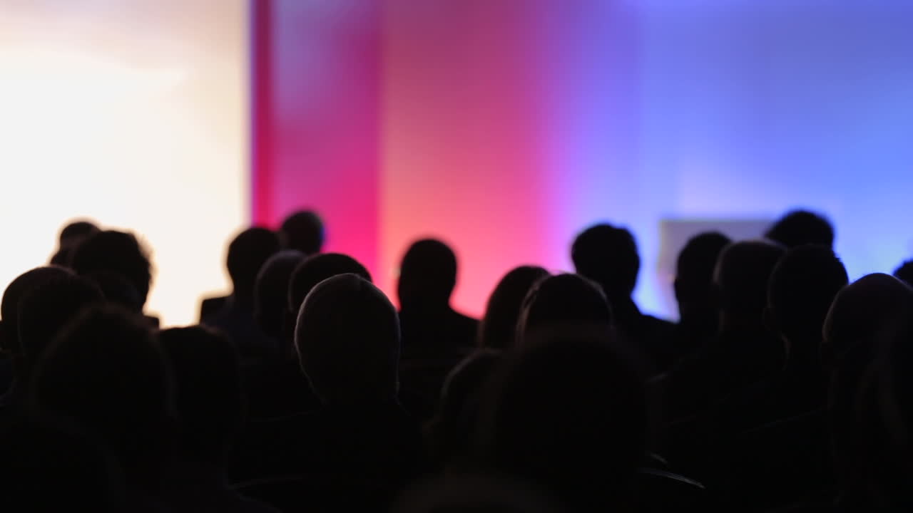Silhouette of a seated crowd in an event conference hall.