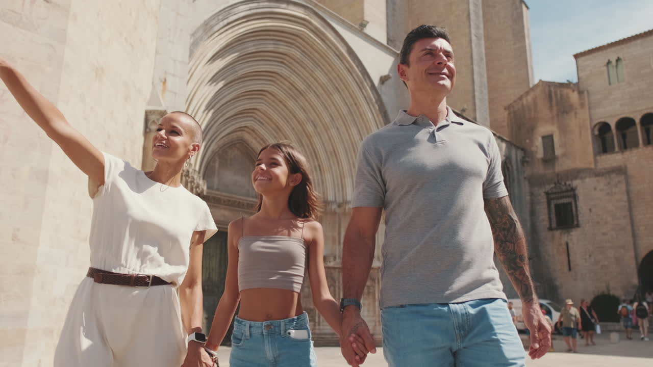 Famiglia felice cammina mano nella mano attraverso una storica città europea