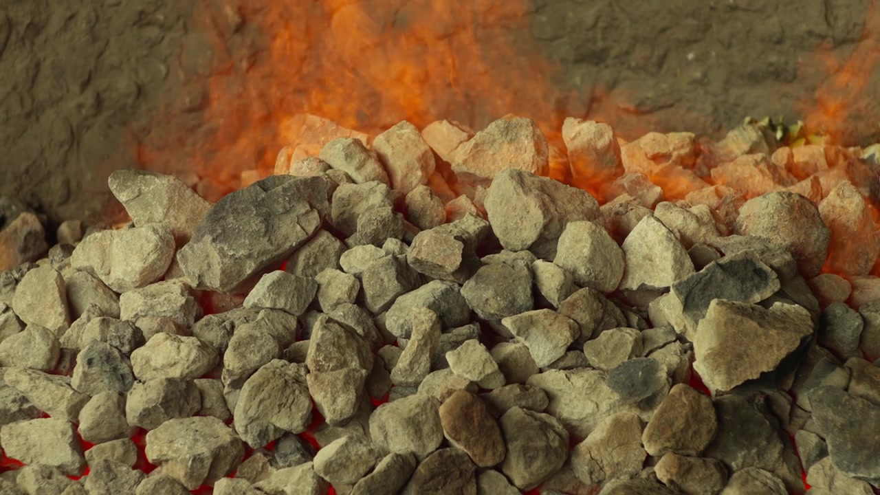 Hot roasting stones inside traditional mezcal oven during agave cooking, preparation for cultural practice