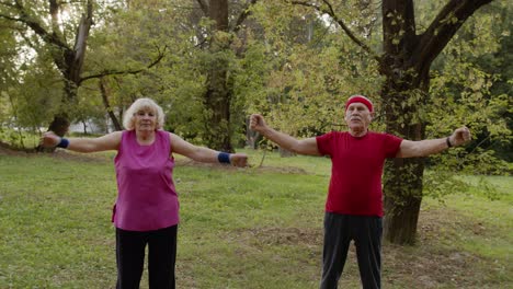 Senior-active-couple-doing-sport-physical-exercises-outdoor-in-city-park.-Morning-stretching-workout