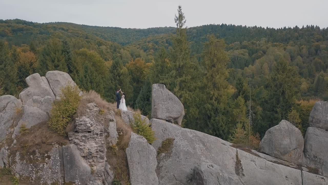 los recién casados están en una ladera alta de la montaña. el novio y la novia. vista aérea