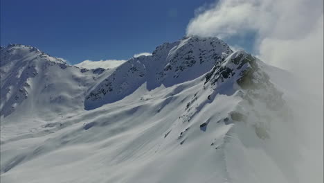 Una-Toma-Aérea-De-Un-Paisaje-Nevado-Blanco-Claro-En-Una-Montaña-En-Un-Clima-Ligeramente-Nublado-En-Austria