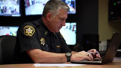 a focused officer analyzing surveillance footage and data from a command center with multiple monitors displaying security feeds and operations information