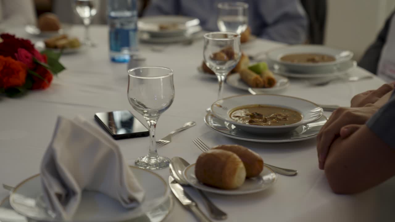 A beautifully set table at a formal banquet or corporate event. Guests are enjoying the first course of soup at a professional luncheon or gala dinner