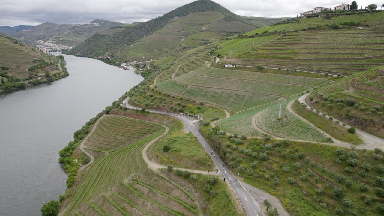 Ripresa aerea di ciclisti che pedalano in salita su strade tortuose tra i vigneti lungo il fiume Douro in Portogallo