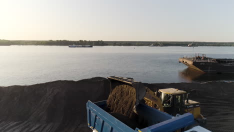 excavator loading dumper truck on riverbank