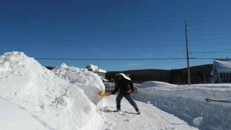 Man-piling-snow-with-a-shovel-to-clear-driveway