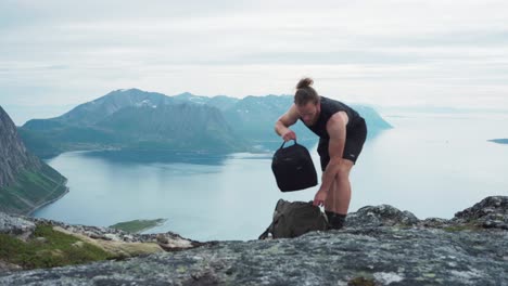 Kaukasischer-Mann-Wechselt-Hemd-Auf-Dem-Gipfel-Der-Felsberge-In-Salberget,-Norwegen