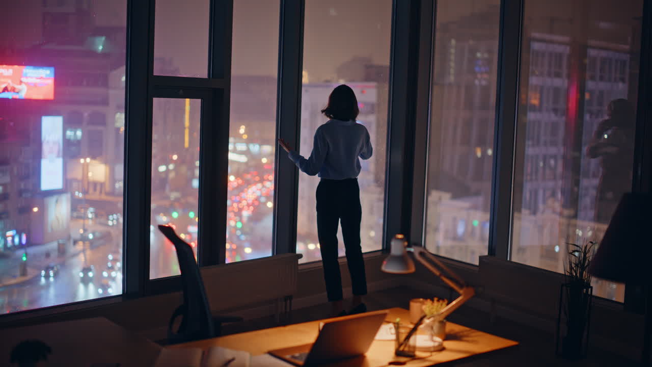 Corporate leader talking cellphone at dark office by panoramic window back view