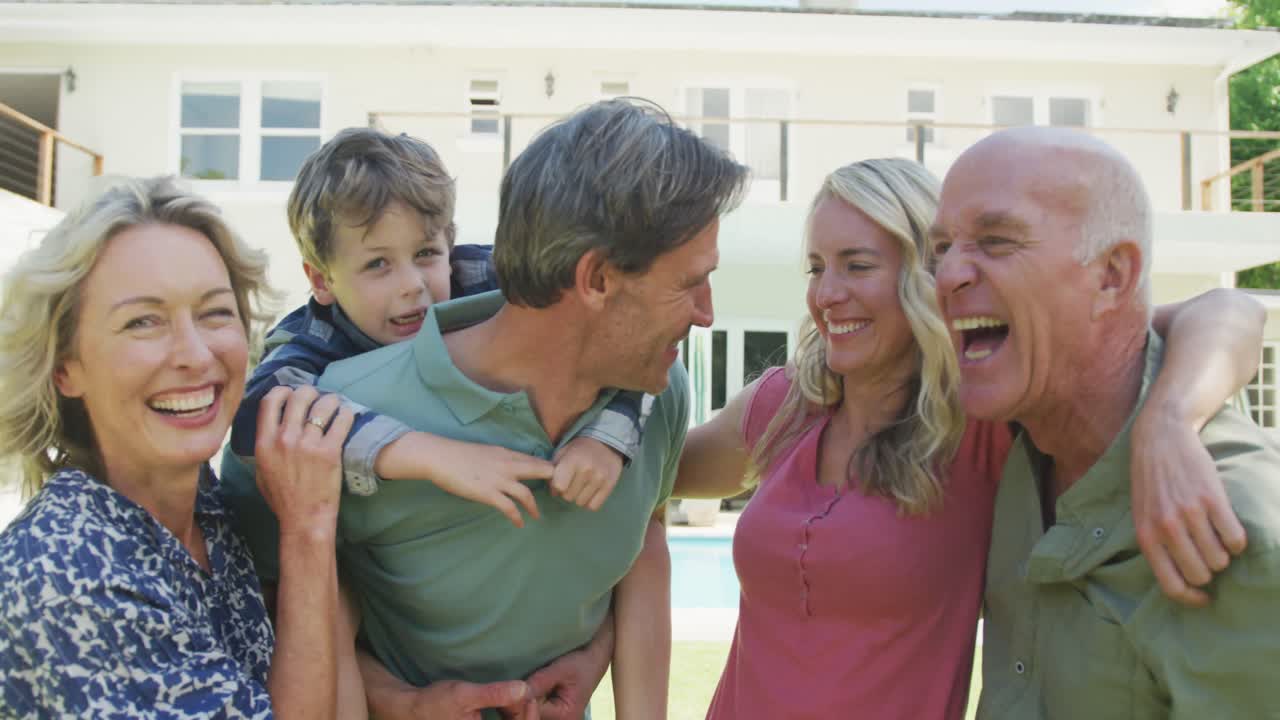 정원에서 카메라를 보는 행복한 백인 가족의 초상화