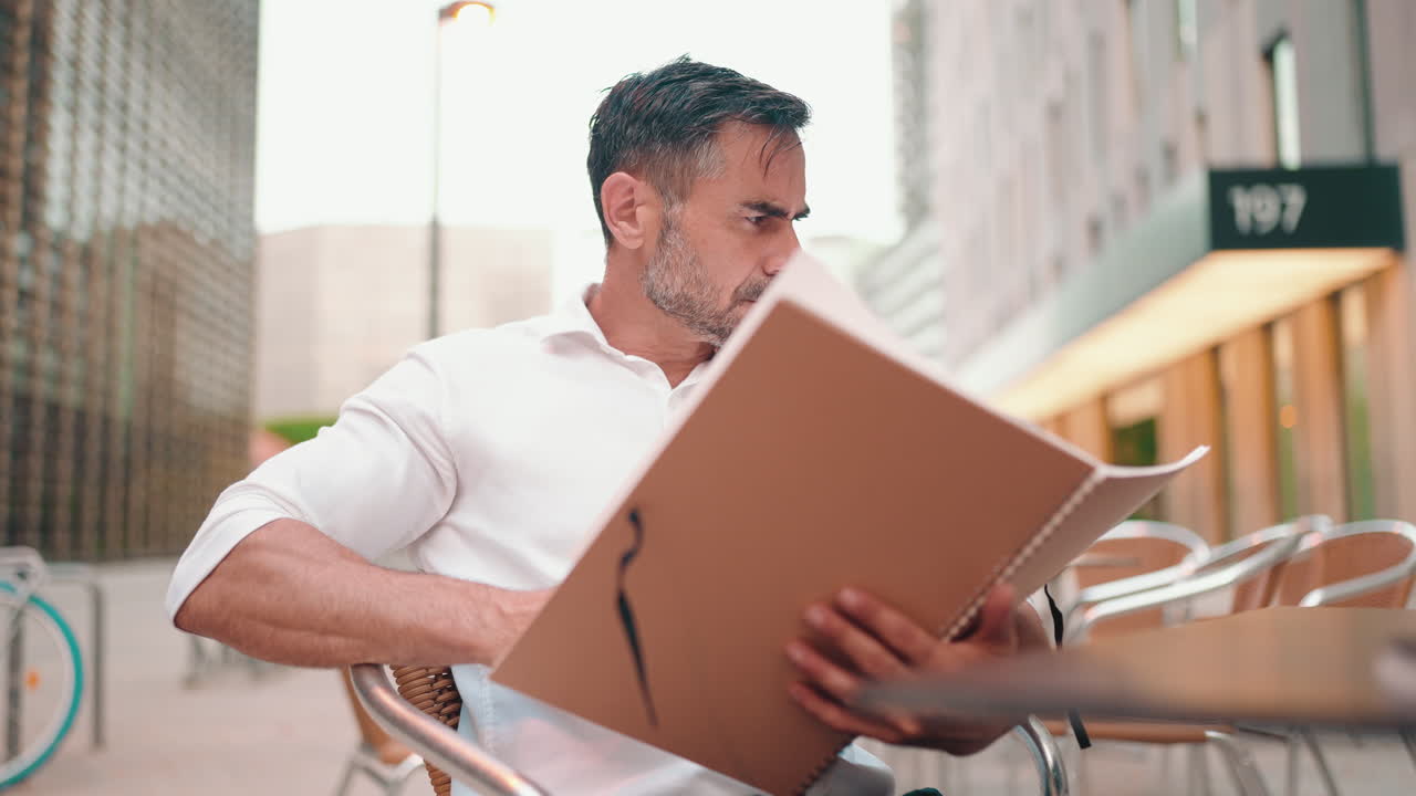 Man reading a menu at an outdoor cafe