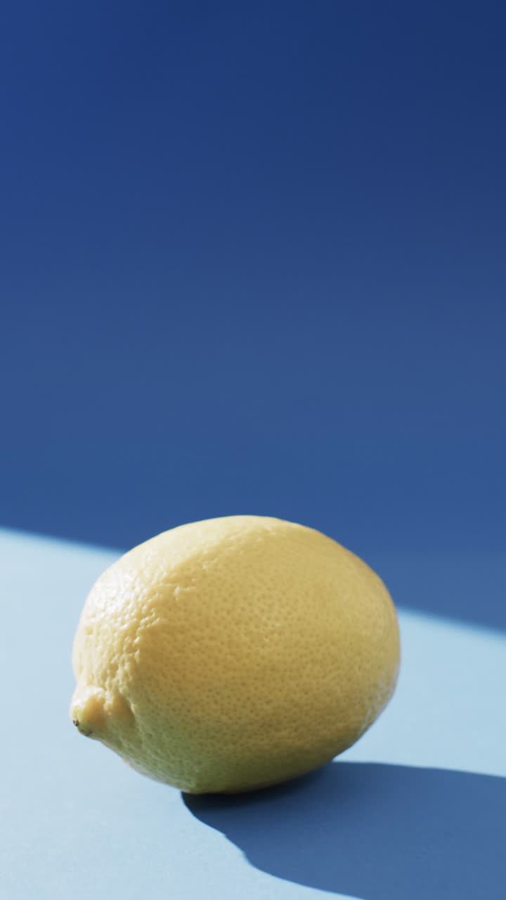 Vertical video of lemon with copy space on blue background