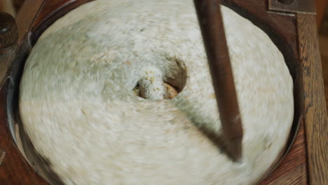 el panadero muele el grano en harina. molino de mano antiguo en funcionamiento con una auténtica piedra de molino de 200 años