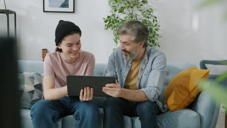 father and son using tablet together at home