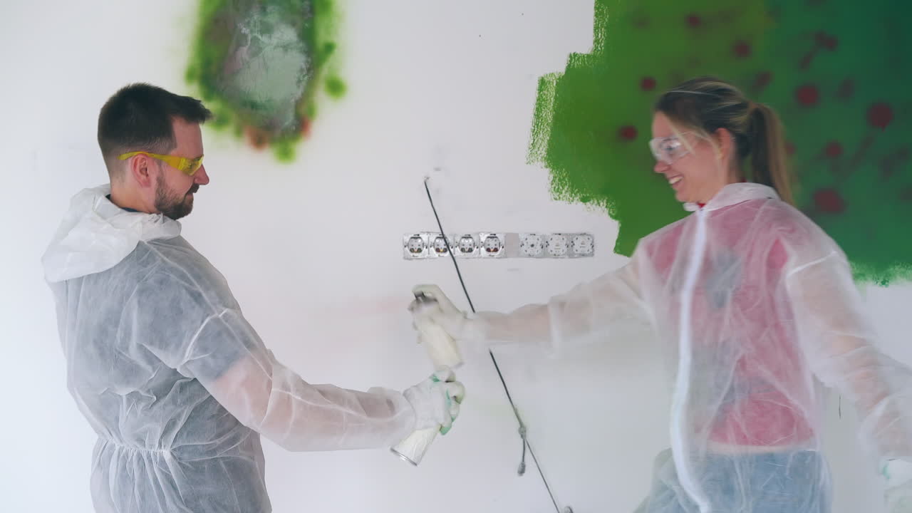 la familia en trajes transparentes pinta la pared con sprays