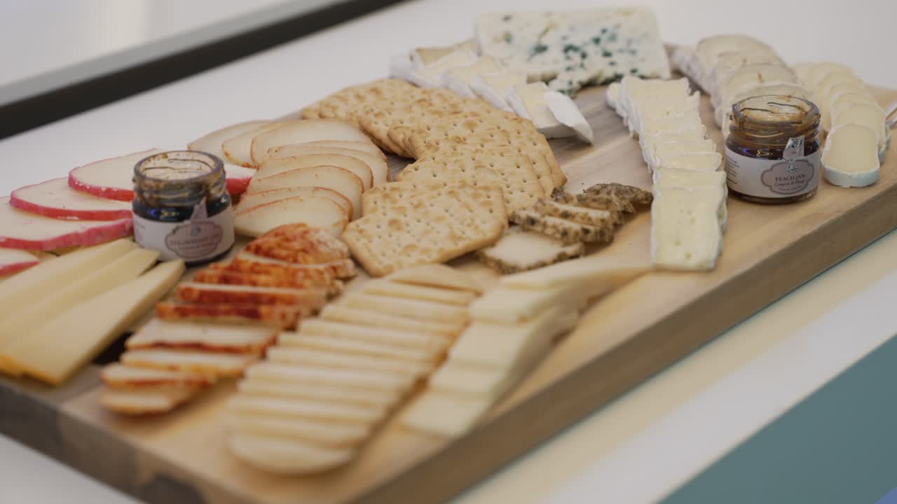 Assorted cheese and cracker platter with fruit and spreads on wood board