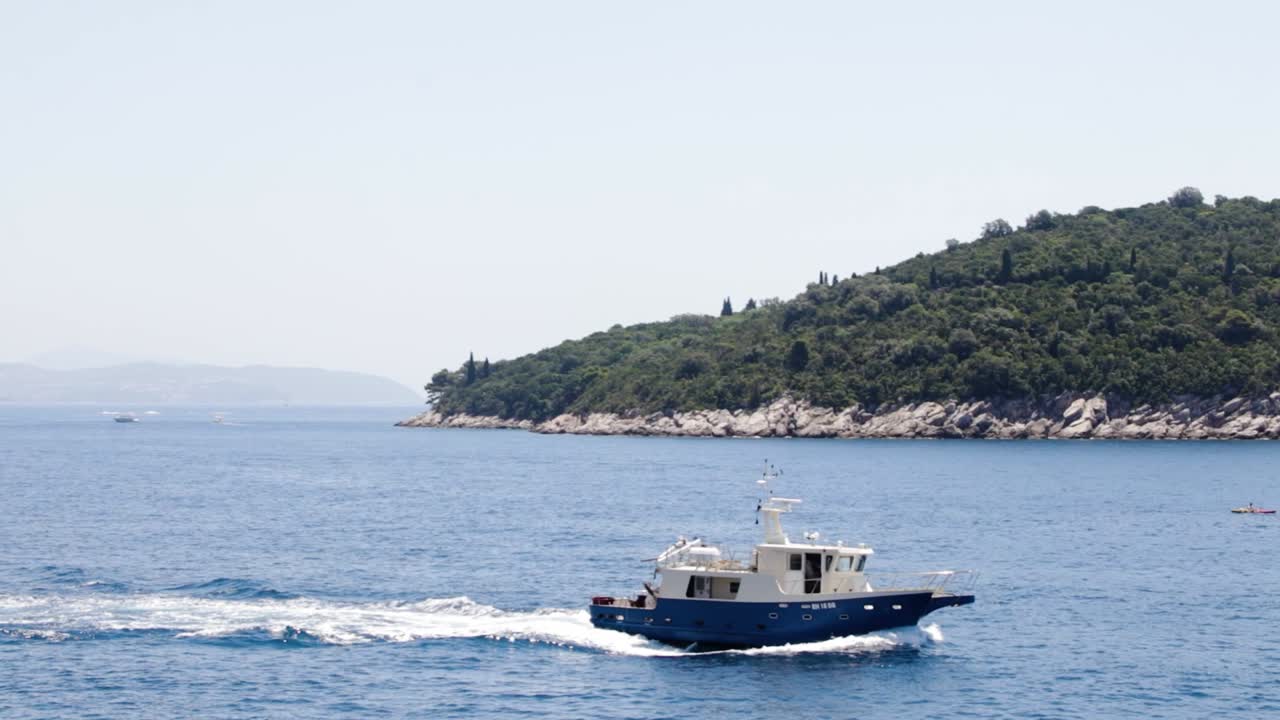 barco de pesca saliendo al mar para pescar con la isla otok lokrum en el fondo en dubrovnik, croacia