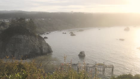 amanecer tranquilo sobre un muelle de pesca en la costa de califonia, luz dorada sobre una cala