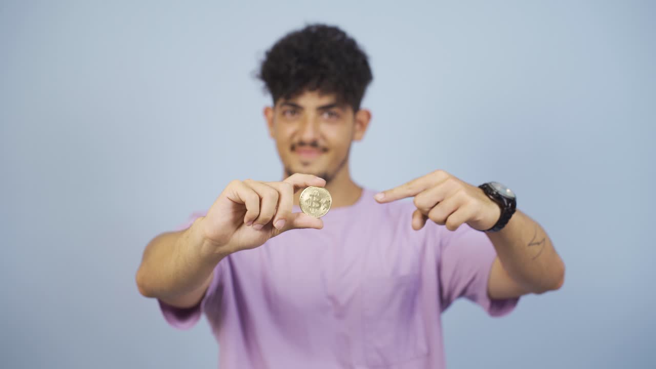 Uomo che tiene in mano e mostra un bitcoin