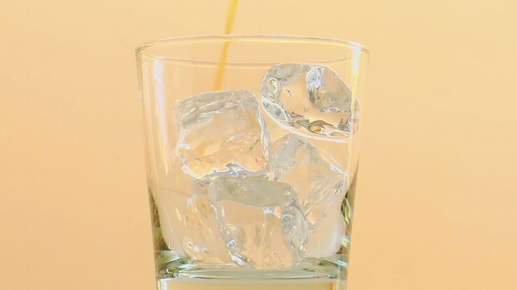 Liquor is poured into a glass with ice 1