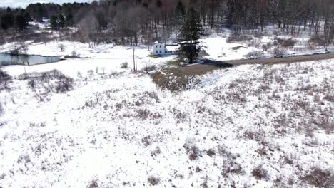 Imágenes-Aéreas-De-Drones-Alejándose-De-Una-Vieja-Casa-Blanca-Para-Revelar-El-Campo-Y-El-Bosque-Cubiertos-De-Nieve