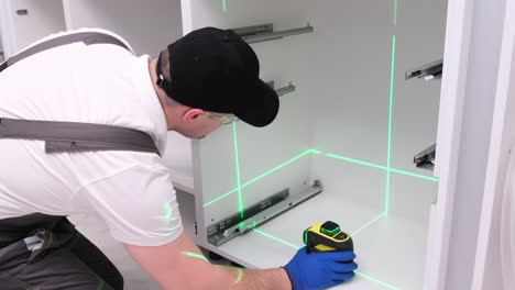 a man collects kitchen furniture repair of the kitchen using a construction laser