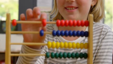 front view of caucasian schoolgirl learning mathematics with abacus in the classroom 4k