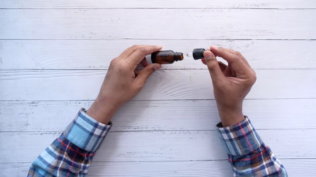 Mani che Aprono una Bottiglia di Olio Essenziale