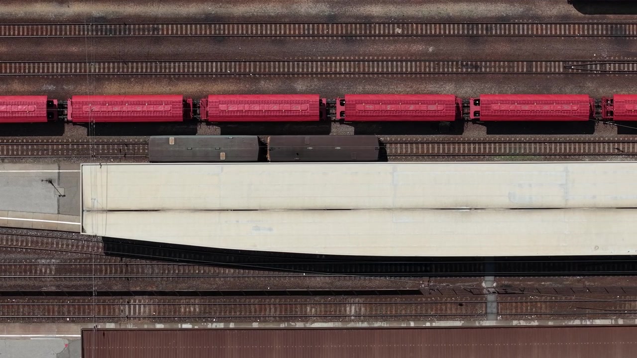 Una vista aérea de un tren de carga rojo descansando en las vías del tren en una estación en Hungría, mostrando el transporte industrial.