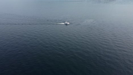 Drone-crane-shot-of-a-pontoon-boat-driving-from-right-to-left-on-Payette-Lake-in-McCall,-Idaho