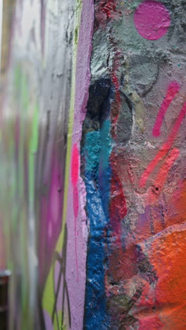 Vertical-Video-Close-Up-Detail-Of-Colourful-Graffitti-Spray-Painted-Onto-Wall-In-London-City-Street-UK