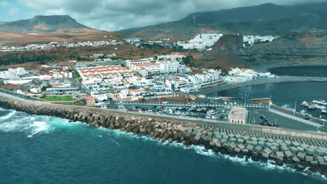 Maravillosa-Vista-Aérea-Del-Pueblo-De-Agete-Y-Donde-Se-Puede-Ver-Su-Puerto,-Sus-Casas-Y-Su-Playa