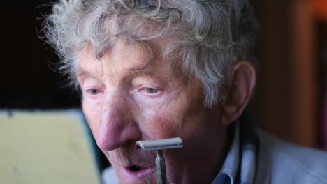 Elderly man grooming himself with a mirror