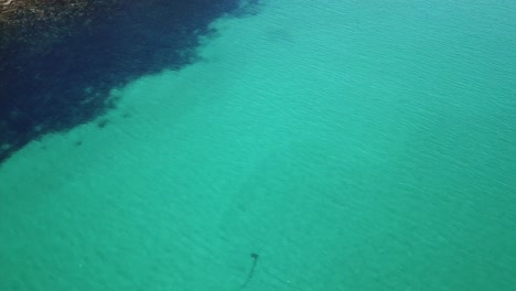 antena de drones sobre agua azul tropical en un día soleado con arrecife