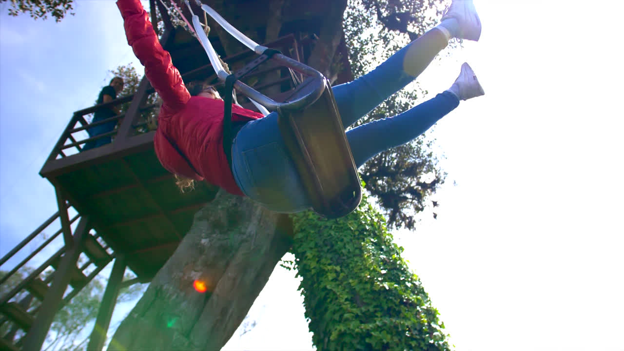 mujer caucásica feliz en un columpio con los brazos abiertos