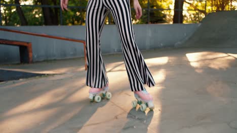 portrait of a girl with a short haircut in a purple top and striped pants rides on pink roller skates in an outdoor skatepark in summer