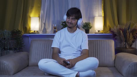 우울한 남자가 밤에 집에서 음악을 듣고 있습니다.