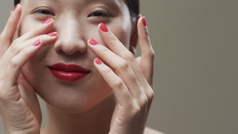 mujer asiática con cabello negro, labios rojos y maquillaje sonriente, copia espacio, cámara lenta