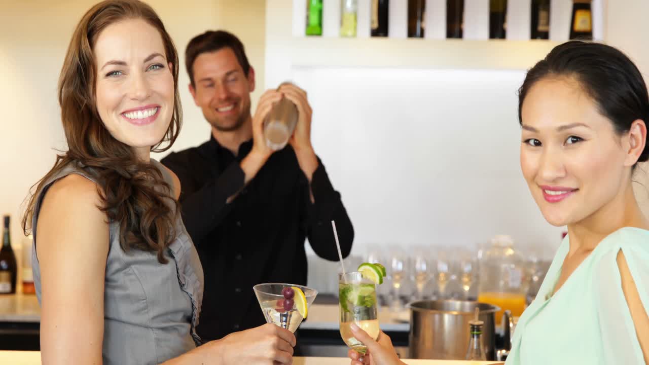 amigos bonitos viendo el cantinero agitar un cóctel