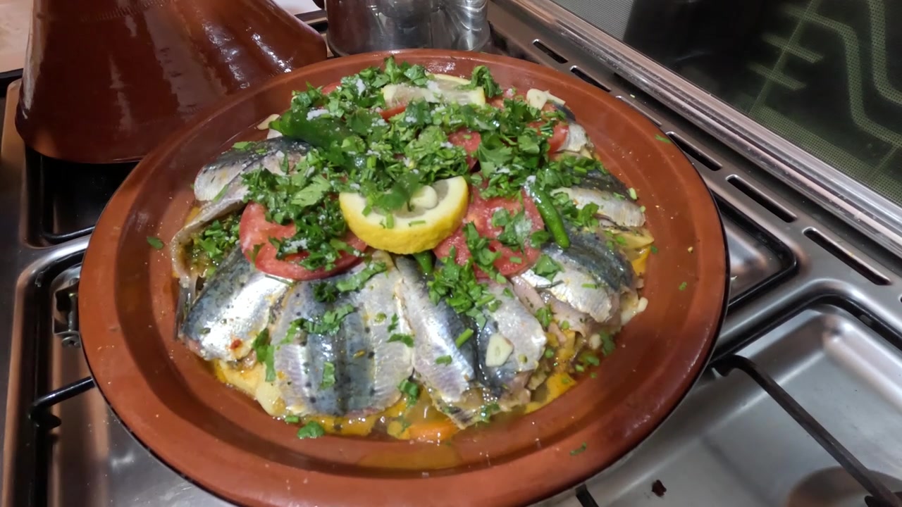 Cozinhando tagine marroquino em forno a gás com sardinhas e vegetais, exibindo a culinária tradicional, sabores ricos e uma refeição caseira, inspirada na costa, em uma atmosfera de cozinha acolhedora